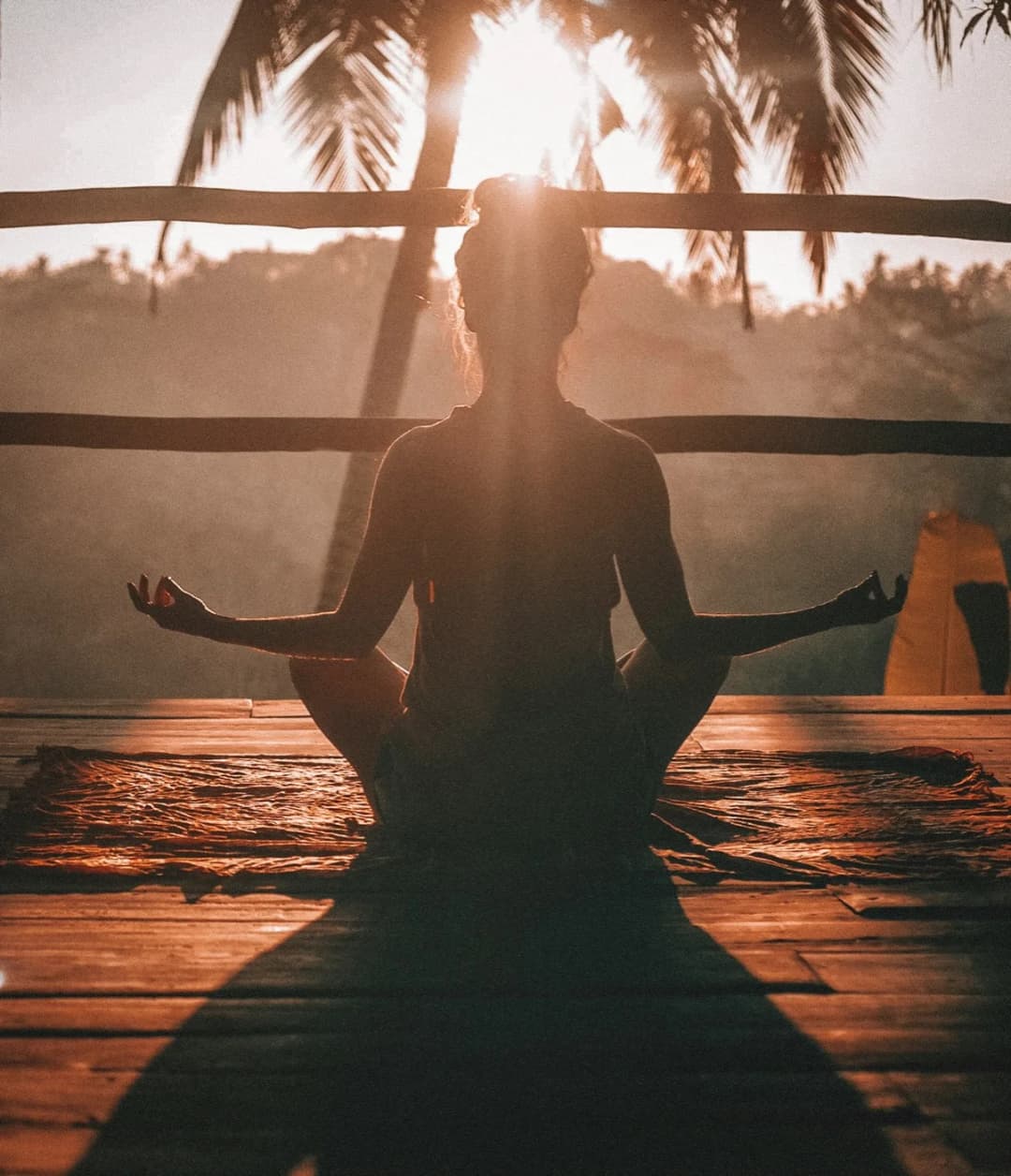 Person in Meditationshaltung im Gegenlicht der Morgensonne